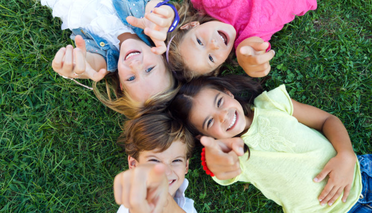 Wil jij deze vakantie de hand op de knip houden, maar niet elke dag binnen zitten met de kids? Bekijk dan hier onze beste Goedkope uitjes met kinderen. Hier liggen de kinderen in het gras en wijzen lachend naar boven.
